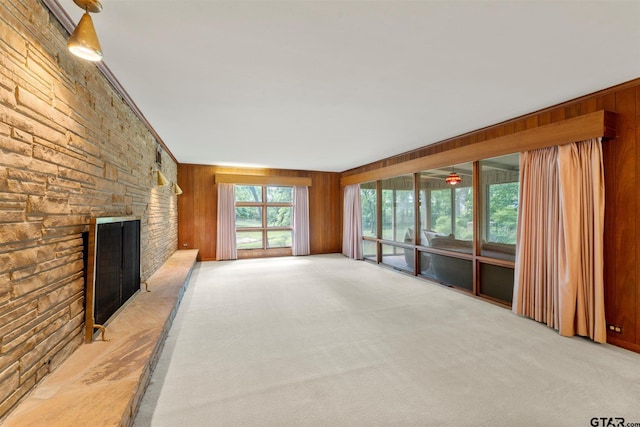 unfurnished living room with wooden walls, carpet flooring, and a fireplace