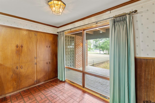 doorway to outside featuring wooden walls, crown molding, and brick patterned floor
