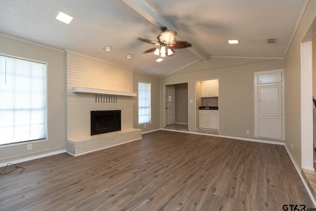 unfurnished living room featuring vaulted ceiling with beams, a fireplace, visible vents, and wood finished floors