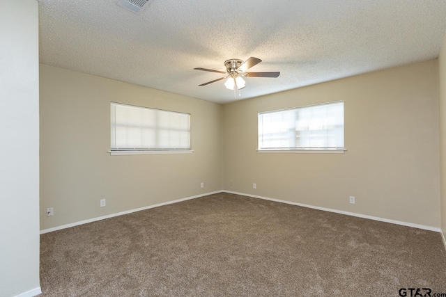 carpeted empty room featuring a ceiling fan, visible vents, a textured ceiling, and baseboards