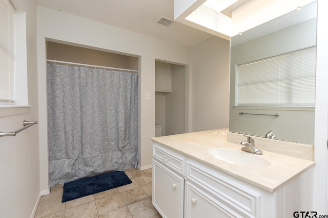 full bathroom with visible vents, vanity, a textured ceiling, tile patterned flooring, and baseboards