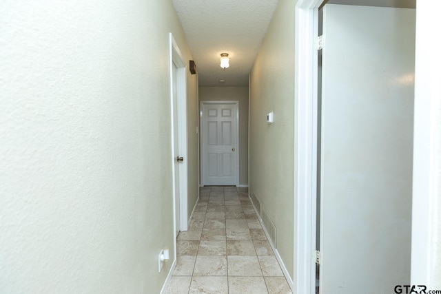 hallway with a textured ceiling and baseboards