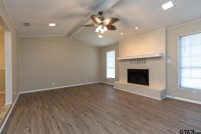 unfurnished living room with a brick fireplace, lofted ceiling with beams, a textured ceiling, and wood finished floors