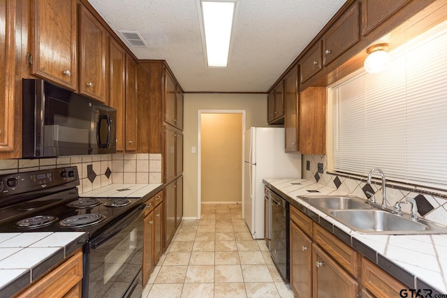 kitchen with tile countertops, black appliances, a sink, and visible vents