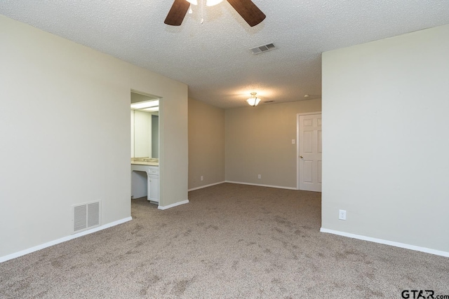 empty room with a textured ceiling, carpet, visible vents, and baseboards