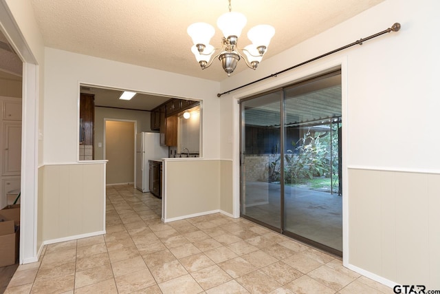 interior space with freestanding refrigerator, wainscoting, light countertops, and a textured ceiling