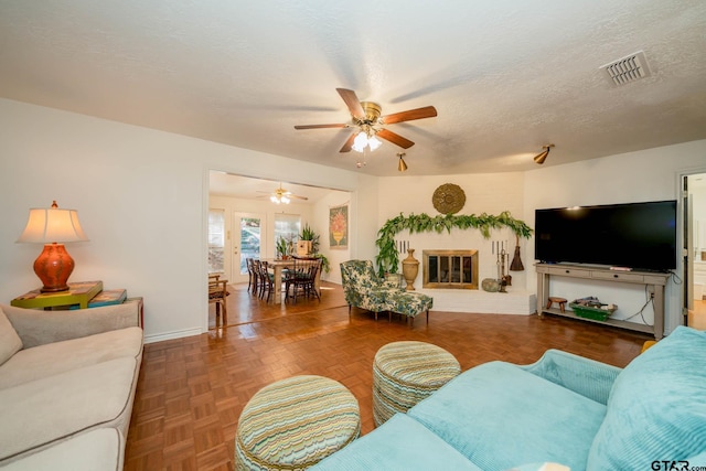 living room featuring ceiling fan, dark parquet flooring, and a textured ceiling