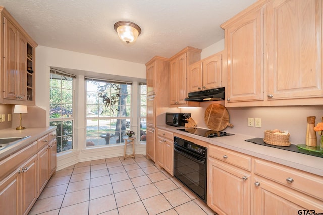 kitchen with a textured ceiling, light tile patterned floors, light brown cabinets, and black appliances