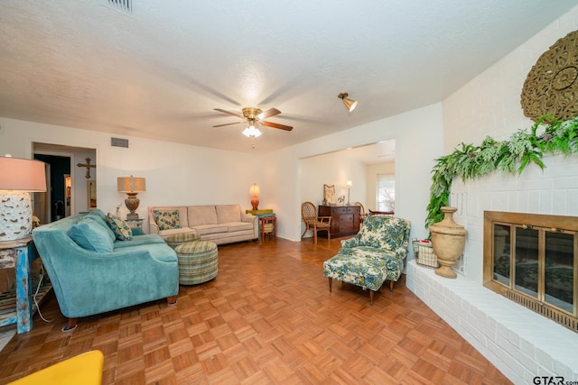 living room with parquet flooring, a brick fireplace, and a textured ceiling