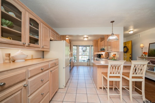 kitchen with light tile patterned flooring, light brown cabinets, a kitchen breakfast bar, and decorative light fixtures