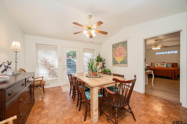 dining area with ceiling fan, vaulted ceiling, and light parquet floors