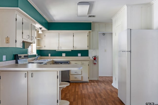 kitchen featuring kitchen peninsula, hardwood / wood-style floors, stainless steel dishwasher, white cabinets, and white fridge