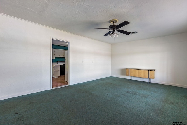 empty room with a textured ceiling, dark colored carpet, ceiling fan, and crown molding