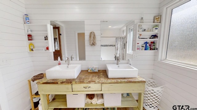 bathroom with sink, wooden walls, and a healthy amount of sunlight