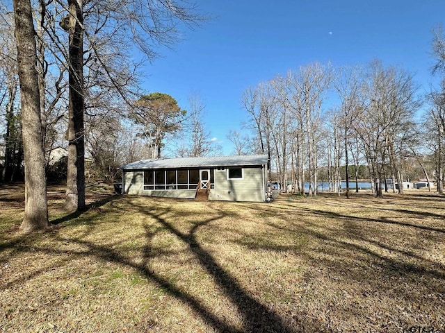 rear view of house with a water view, a yard, and a sunroom