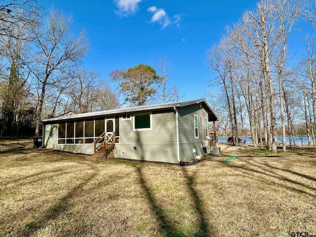 rear view of property with a water view, a yard, central air condition unit, and a sunroom