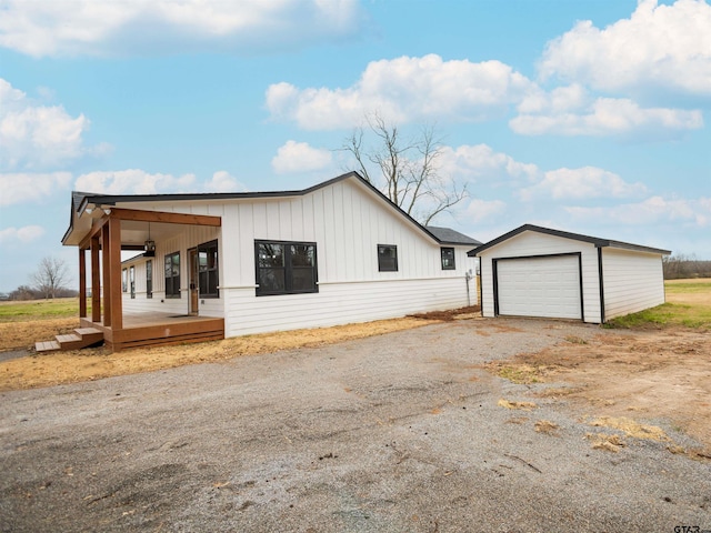 view of property exterior with board and batten siding, driveway, an outdoor structure, a detached garage, and a porch