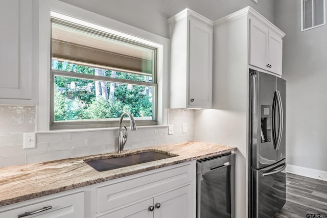 1534 Cimmarron Trl, Tyler, TX 75703 - kitchen with stainless steel appliances, a sink, wood finished floors, white cabinetry, and decorative backsplash