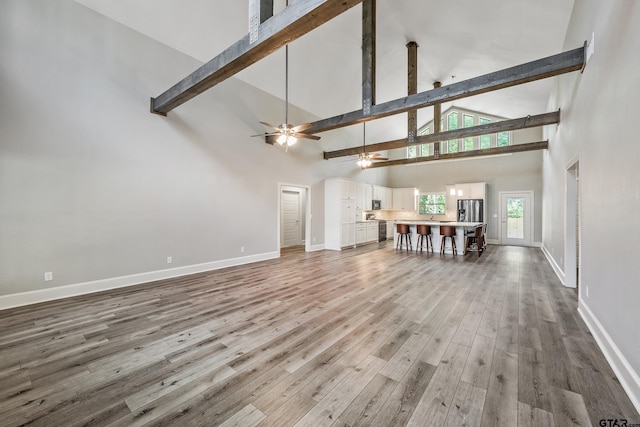 1534 Cimmarron Trl, Tyler, TX 75703 - living room with high vaulted ceiling, baseboards, beamed ceiling, wood finished floors, and a ceiling fan