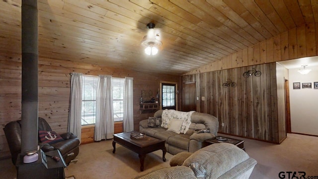 living room featuring wooden ceiling, wood walls, a healthy amount of sunlight, and a wood stove