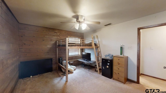 bedroom with light colored carpet, wood walls, and ceiling fan