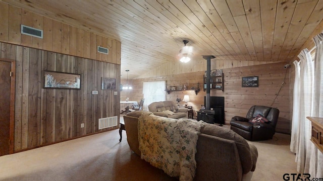 carpeted living room with a wood stove, lofted ceiling, wooden walls, and wooden ceiling