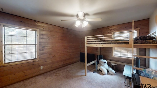 bedroom with wooden walls, carpet, and ceiling fan