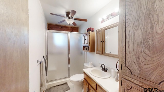 bathroom featuring ceiling fan, a shower with door, vanity, and toilet