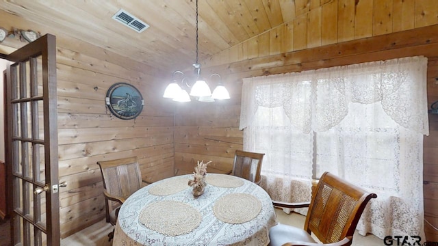 dining area with wooden ceiling, wood walls, an inviting chandelier, and vaulted ceiling