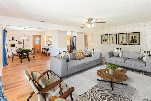 living room featuring hardwood / wood-style flooring, ceiling fan, and a textured ceiling