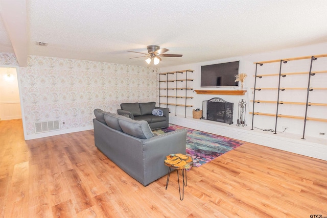 living room featuring beam ceiling, ceiling fan, a textured ceiling, and hardwood / wood-style flooring