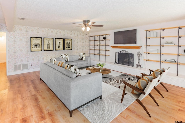 living room with ceiling fan, wood-type flooring, and a textured ceiling