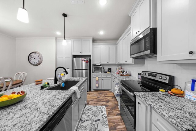 kitchen with stainless steel appliances, sink, decorative light fixtures, white cabinets, and dark hardwood / wood-style flooring