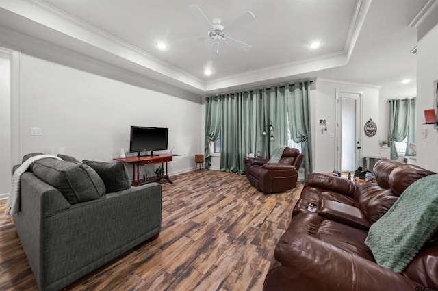 living room with ceiling fan, a raised ceiling, dark hardwood / wood-style flooring, and ornamental molding