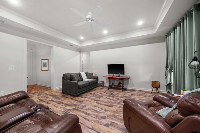 living room with ornamental molding, a tray ceiling, hardwood / wood-style flooring, and ceiling fan