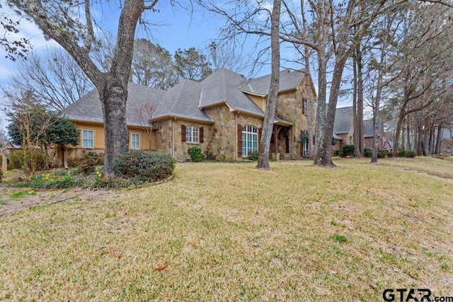 view of front of house with a front yard and stone siding