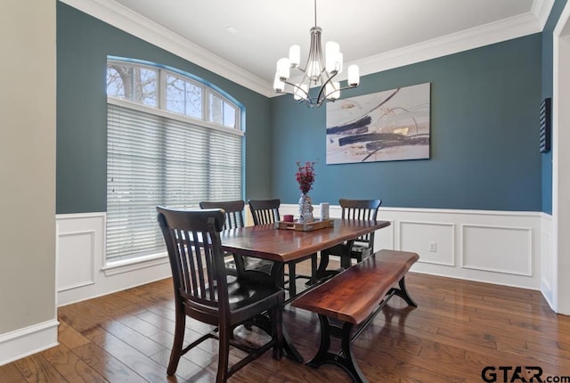 dining area with an inviting chandelier, dark wood finished floors, crown molding, and wainscoting