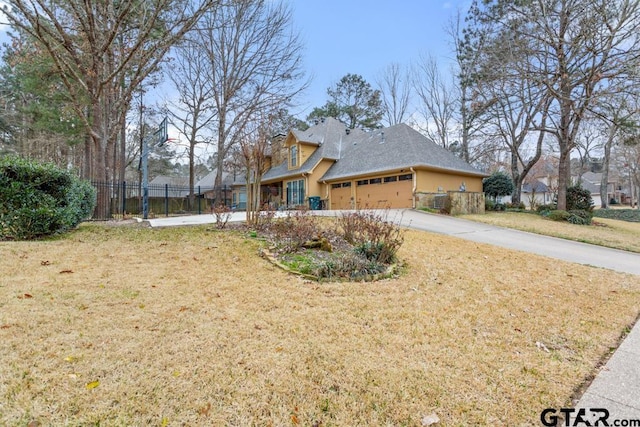 view of side of property with driveway, a lawn, an attached garage, and fence