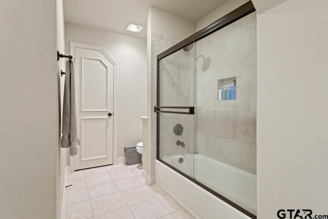 bathroom featuring tile patterned flooring, enclosed tub / shower combo, and toilet