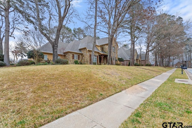 view of home's exterior with stone siding and a lawn