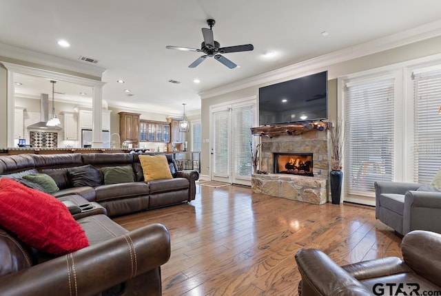 living room featuring crown molding, visible vents, a fireplace, and wood finished floors