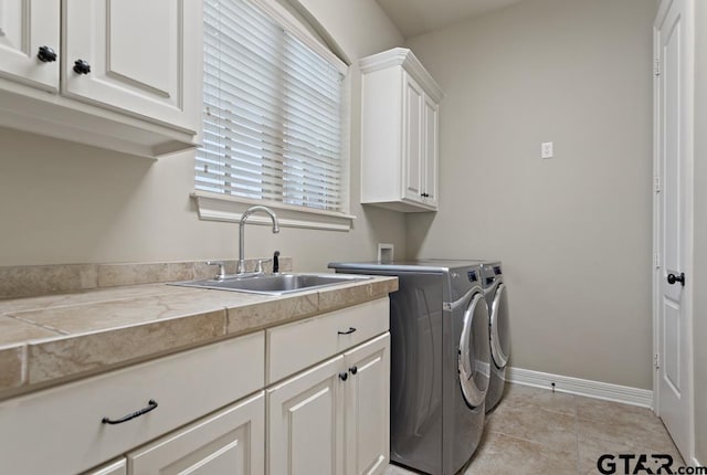 laundry room with cabinet space, light tile patterned floors, baseboards, independent washer and dryer, and a sink