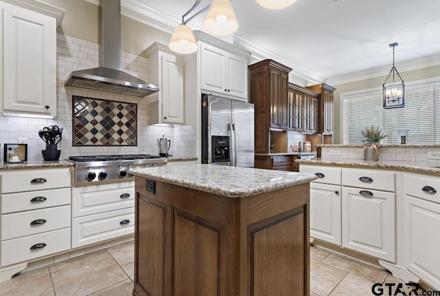 kitchen featuring wall chimney range hood, white cabinetry, appliances with stainless steel finishes, and decorative light fixtures