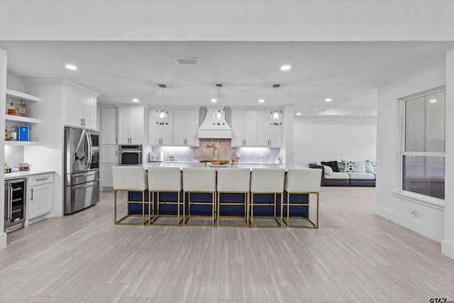 2680 Primera Rd, Tyler, TX 75705 - kitchen with stainless steel appliances, wine cooler, custom range hood, open shelves, and decorative backsplash