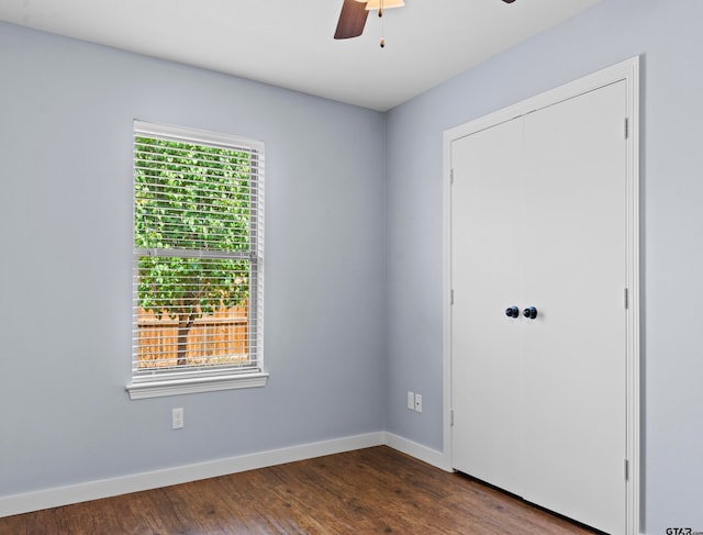 empty room featuring dark wood-type flooring, ceiling fan, and a healthy amount of sunlight