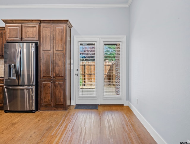 kitchen with light wood-type flooring, stainless steel fridge, and crown molding