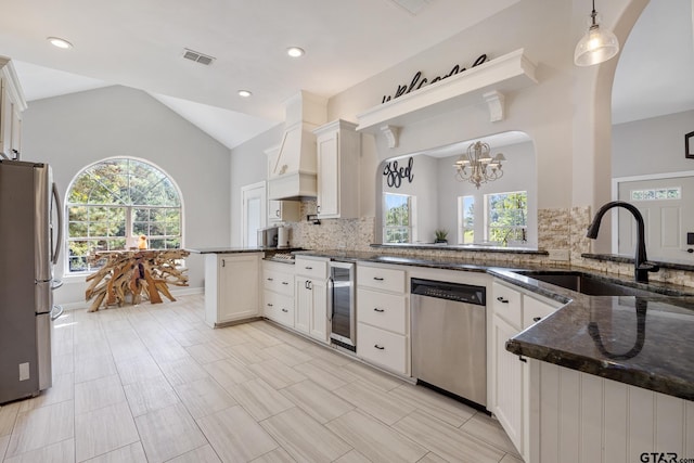 kitchen featuring stainless steel appliances, a wealth of natural light, lofted ceiling, and sink