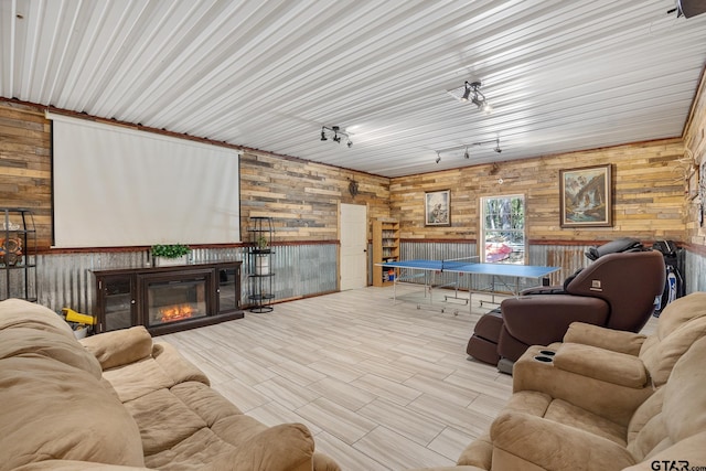 living room featuring light wood-type flooring, rail lighting, and wooden walls