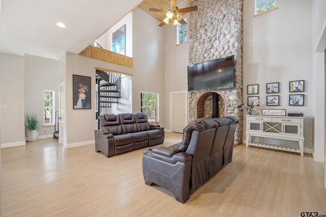 living room featuring a wealth of natural light, a fireplace, a towering ceiling, and light hardwood / wood-style flooring