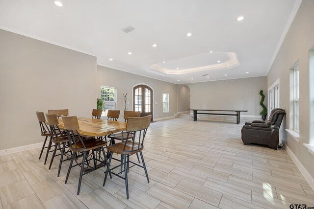 dining room featuring a raised ceiling, ornamental molding, and light hardwood / wood-style flooring